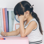 Young brunette girls doing homework or coloring at a table