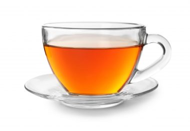 A clear glass cup of tea and saucer